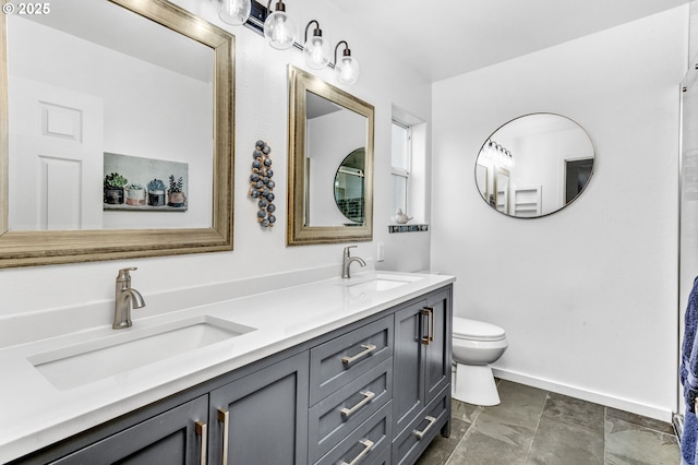 bathroom with double vanity, toilet, baseboards, and a sink