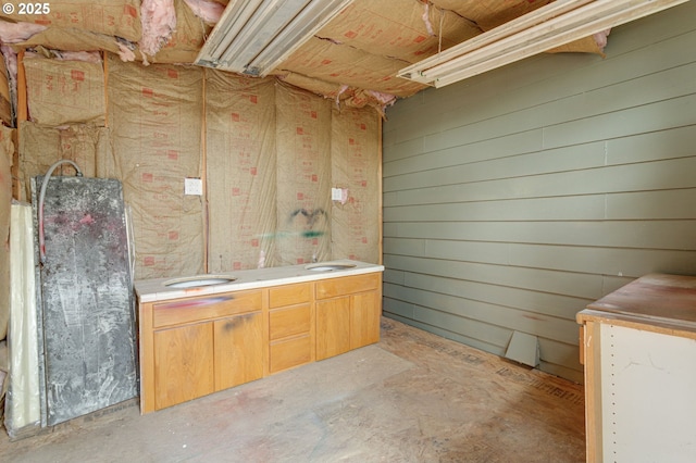 bathroom with concrete flooring and wood walls