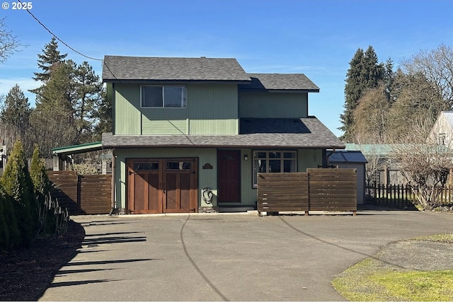 view of front of home with roof with shingles, fence, and asphalt driveway