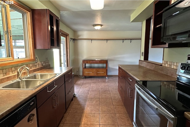 kitchen featuring stainless steel appliances, a sink, plenty of natural light, and glass insert cabinets