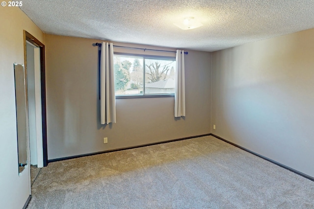 empty room with carpet floors, a textured ceiling, and baseboards