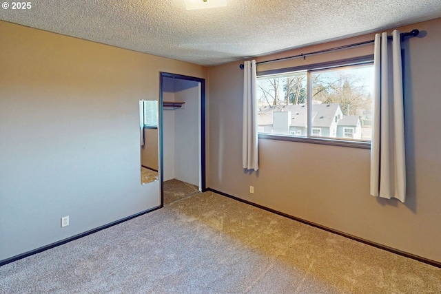 unfurnished bedroom featuring carpet, a textured ceiling, a closet, and baseboards