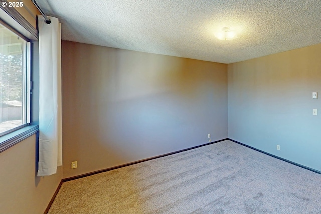 spare room featuring carpet floors, a textured ceiling, and baseboards
