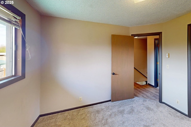 carpeted empty room featuring baseboards and a textured ceiling