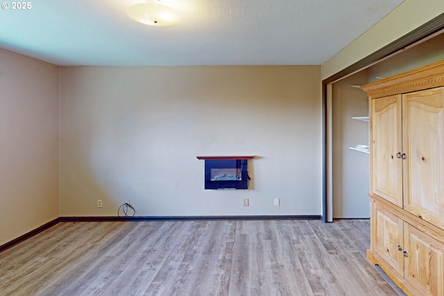 unfurnished living room with light wood-style flooring and baseboards