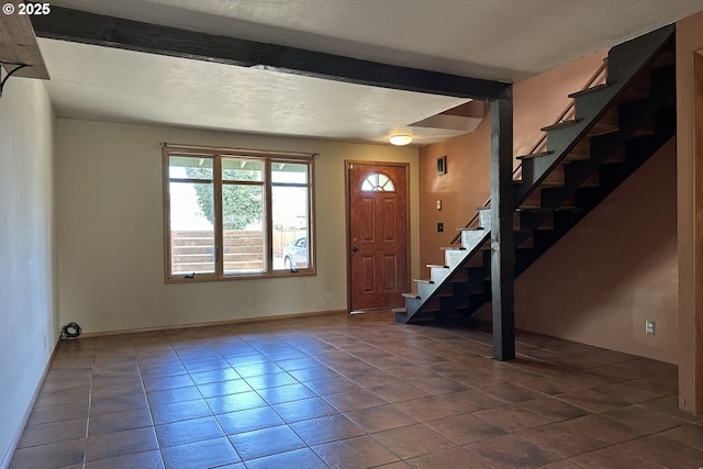 entryway with stairway, dark tile patterned floors, beamed ceiling, and baseboards