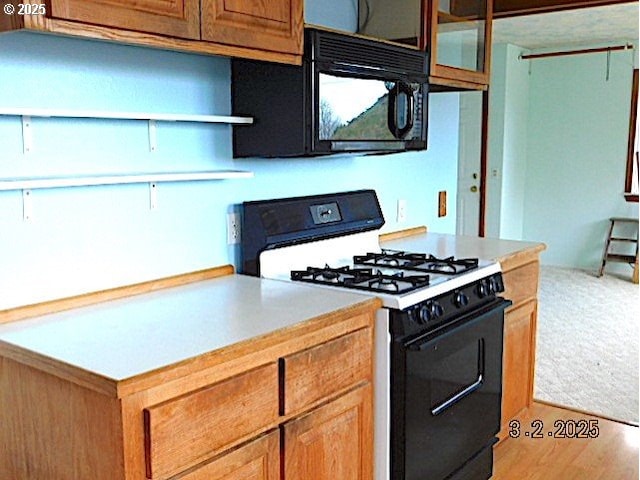 kitchen with black microwave, open shelves, gas stove, and light countertops