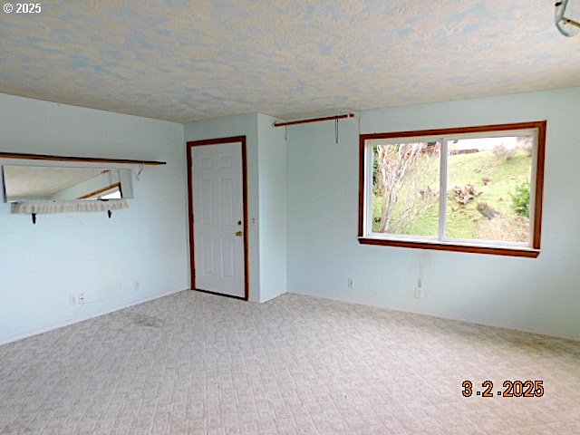 carpeted empty room with a textured ceiling