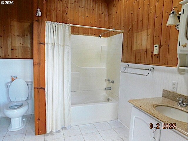 bathroom featuring wooden walls, toilet, shower / tub combo with curtain, tile patterned flooring, and vanity