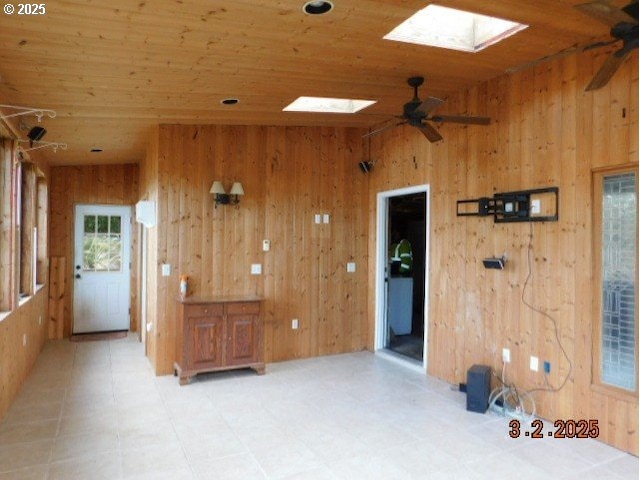 unfurnished room with ceiling fan, wood walls, a skylight, and wooden ceiling