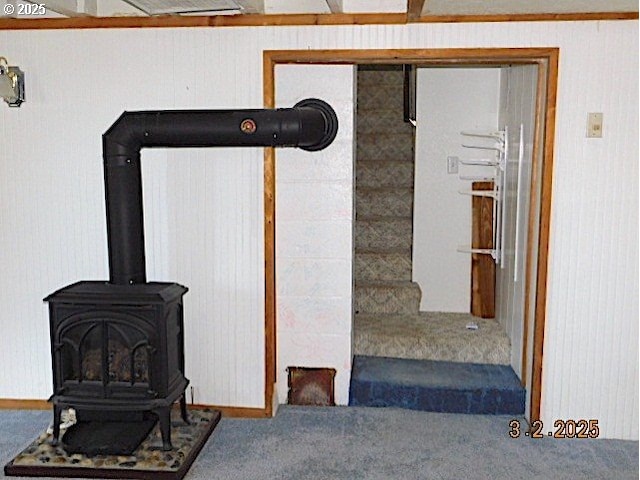 interior space with a wood stove, carpet flooring, and stairs