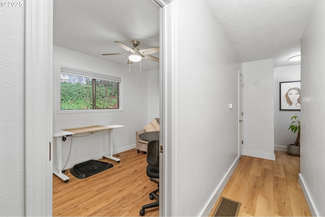 corridor featuring light hardwood / wood-style floors and a textured ceiling