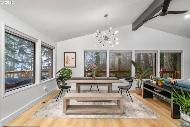 sunroom featuring lofted ceiling with beams and ceiling fan with notable chandelier