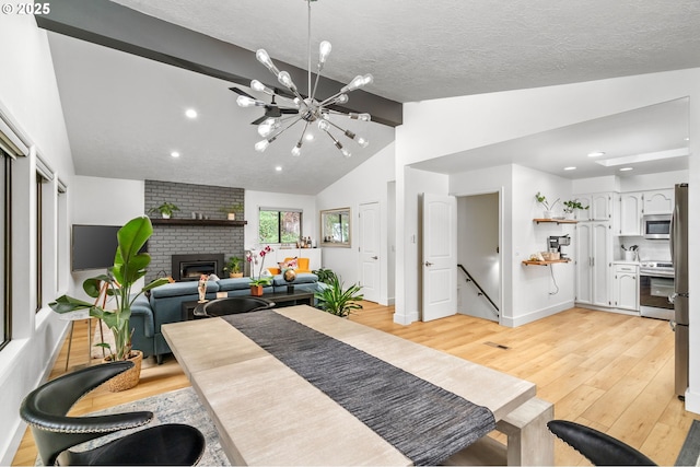 dining area featuring a fireplace, lofted ceiling, light wood-type flooring, a chandelier, and a textured ceiling