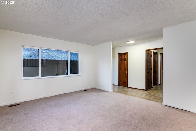 carpeted empty room with a textured ceiling