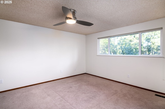 carpeted empty room with ceiling fan and a textured ceiling