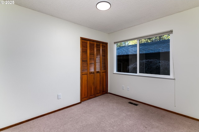 spare room with light colored carpet and a textured ceiling