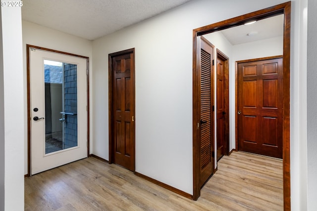 hallway with light hardwood / wood-style flooring and a textured ceiling