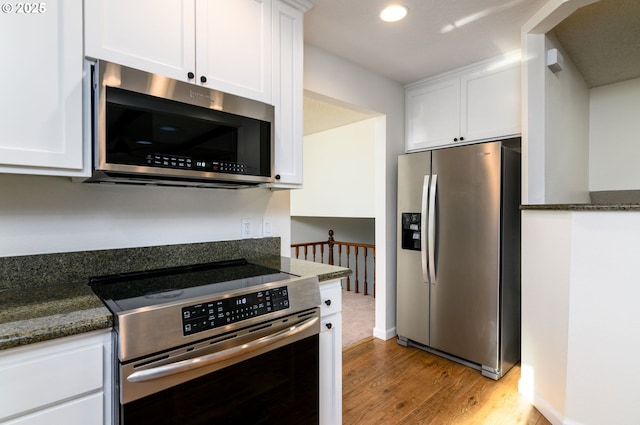 kitchen featuring white cabinetry, light hardwood / wood-style floors, dark stone counters, and appliances with stainless steel finishes