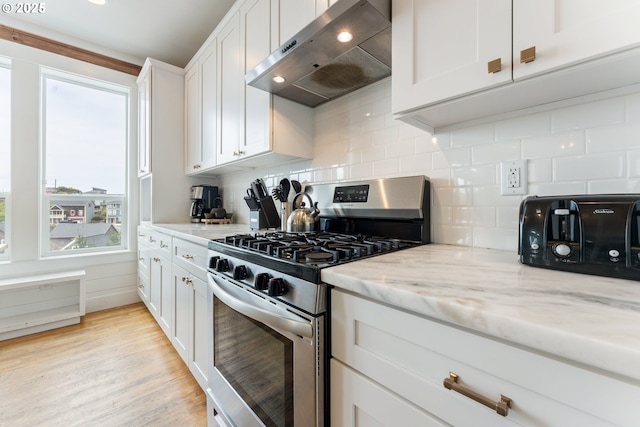 2539 SW Coral Loop, Lincoln City, OR 97367 - kitchen featuring stainless steel gas range, extractor fan, decorative backsplash, light stone counters, and white cabinets
