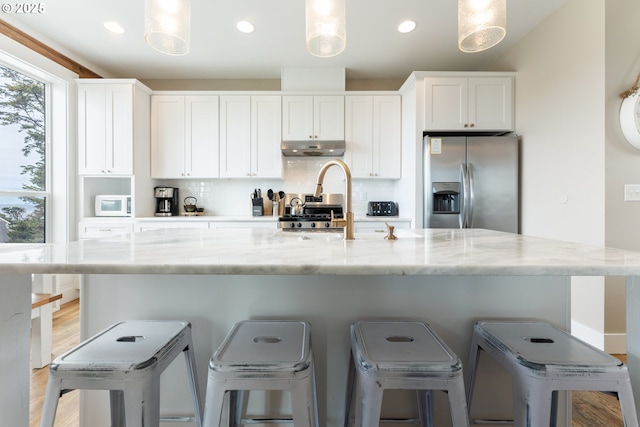 2539 SW Coral Loop, Lincoln City, OR 97367 - kitchen featuring stainless steel fridge, under cabinet range hood, white microwave, white cabinetry, and tasteful backsplash