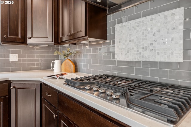 kitchen with stainless steel gas cooktop, backsplash, and dark brown cabinets