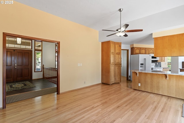 kitchen with white appliances, a kitchen breakfast bar, brown cabinets, and light wood-style floors