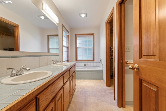 full bath featuring a sink, double vanity, and a bath