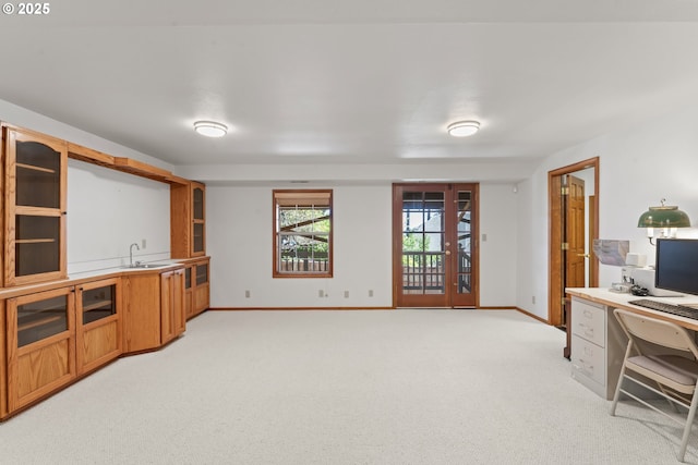 unfurnished office with baseboards, a sink, and light carpet