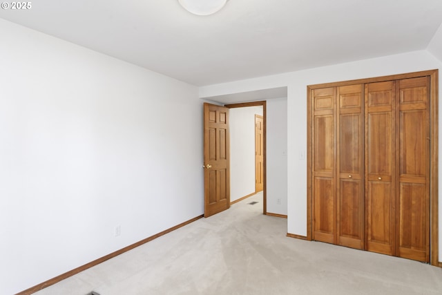 unfurnished bedroom featuring light colored carpet, baseboards, and a closet
