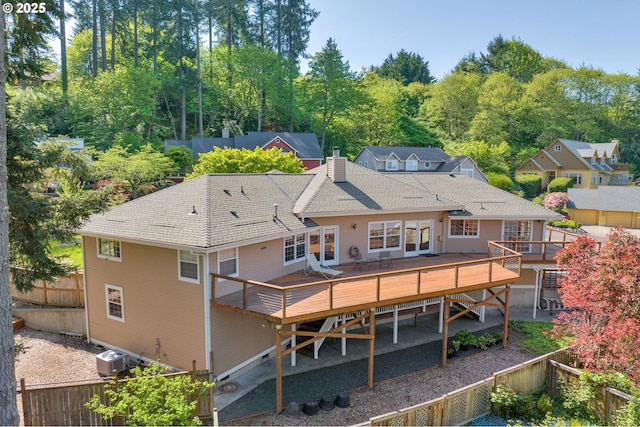 back of house featuring a wooden deck, fence, a chimney, a shingled roof, and central air condition unit