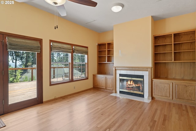 unfurnished living room with baseboards, a fireplace, a ceiling fan, and light wood-style flooring
