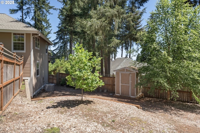 view of yard with central AC, an outbuilding, a fenced backyard, and a storage unit