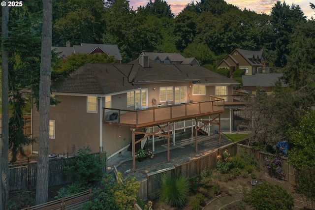 3023 Ashley Loop, Eugene, OR 97405 - back of property at dusk with a fenced backyard, a wooden deck, stairs, and a shingled roof