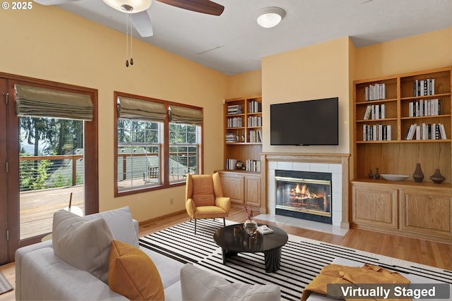 living room featuring a fireplace, a ceiling fan, and light wood-style flooring