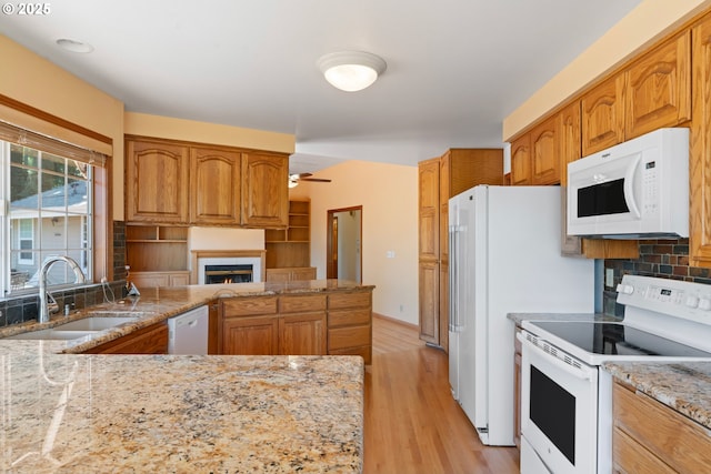kitchen featuring ceiling fan, a sink, white appliances, light wood-type flooring, and a lit fireplace