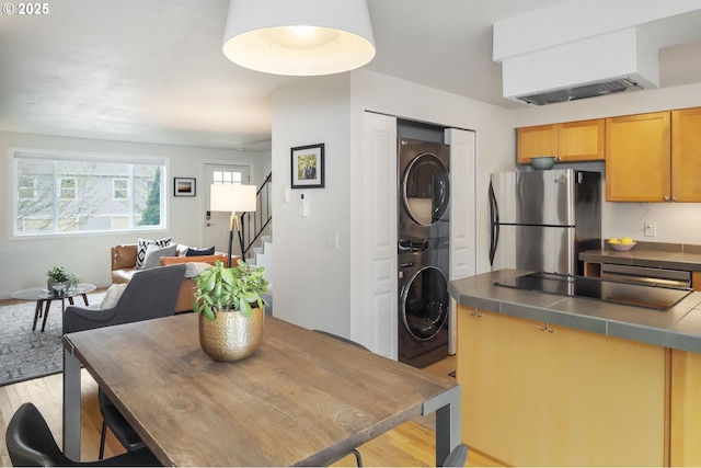 109 NE Shaver Ave, Portland, OR 97212 - dining room featuring stacked washing machine and dryer, light wood finished floors, and stairway