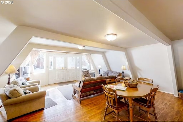 dining area featuring hardwood / wood-style flooring and vaulted ceiling with beams