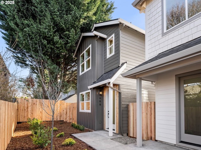 exterior space featuring roof with shingles and fence