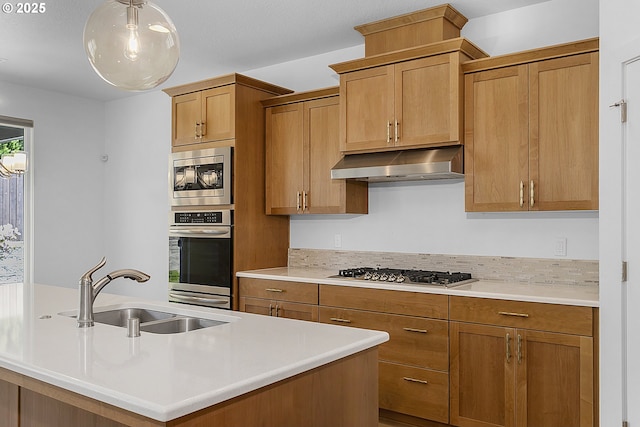 2930 S Cherry Grove Way, Ridgefield, WA 98642 - kitchen featuring brown cabinetry, appliances with stainless steel finishes, a sink, light countertops, and under cabinet range hood