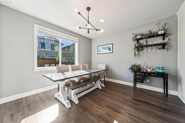 dining area featuring dark wood-style floors, a chandelier, and baseboards