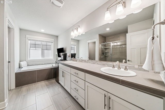 full bathroom featuring a garden tub, a sink, a shower stall, and double vanity