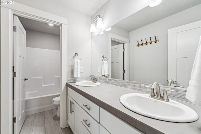 bathroom featuring double vanity, tasteful backsplash, a sink, and toilet