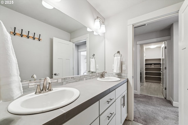 bathroom featuring double vanity, baseboards, visible vents, and a sink