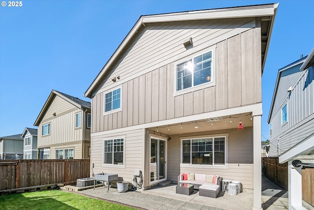 back of house with a yard, a patio, board and batten siding, a fenced backyard, and an outdoor living space