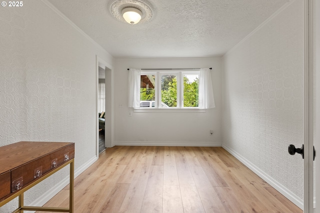 unfurnished room with light wood-style flooring, baseboards, and a textured ceiling