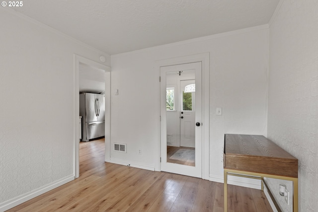 foyer with wood finished floors, crown molding, and baseboards