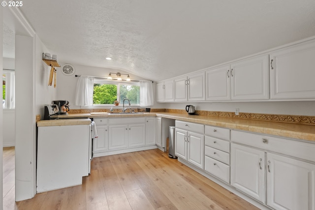 kitchen with a sink, lofted ceiling, white cabinetry, light wood finished floors, and a textured ceiling