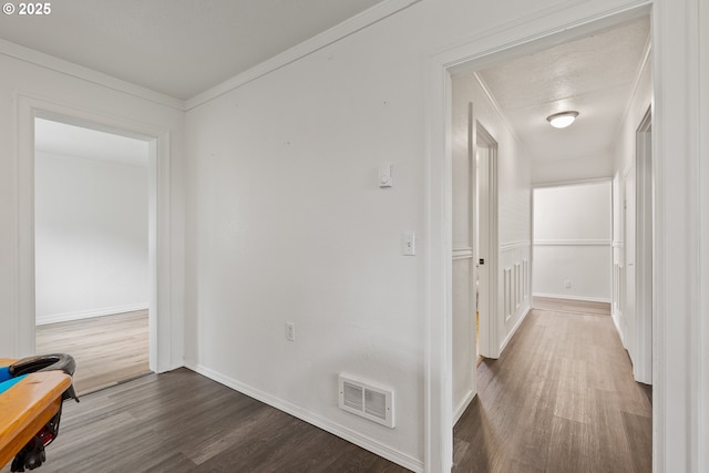 hallway featuring wood finished floors, baseboards, and ornamental molding