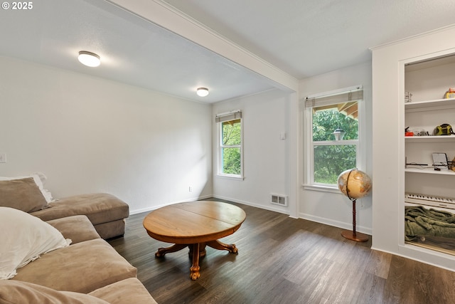 living area with dark wood-style flooring, crown molding, and baseboards